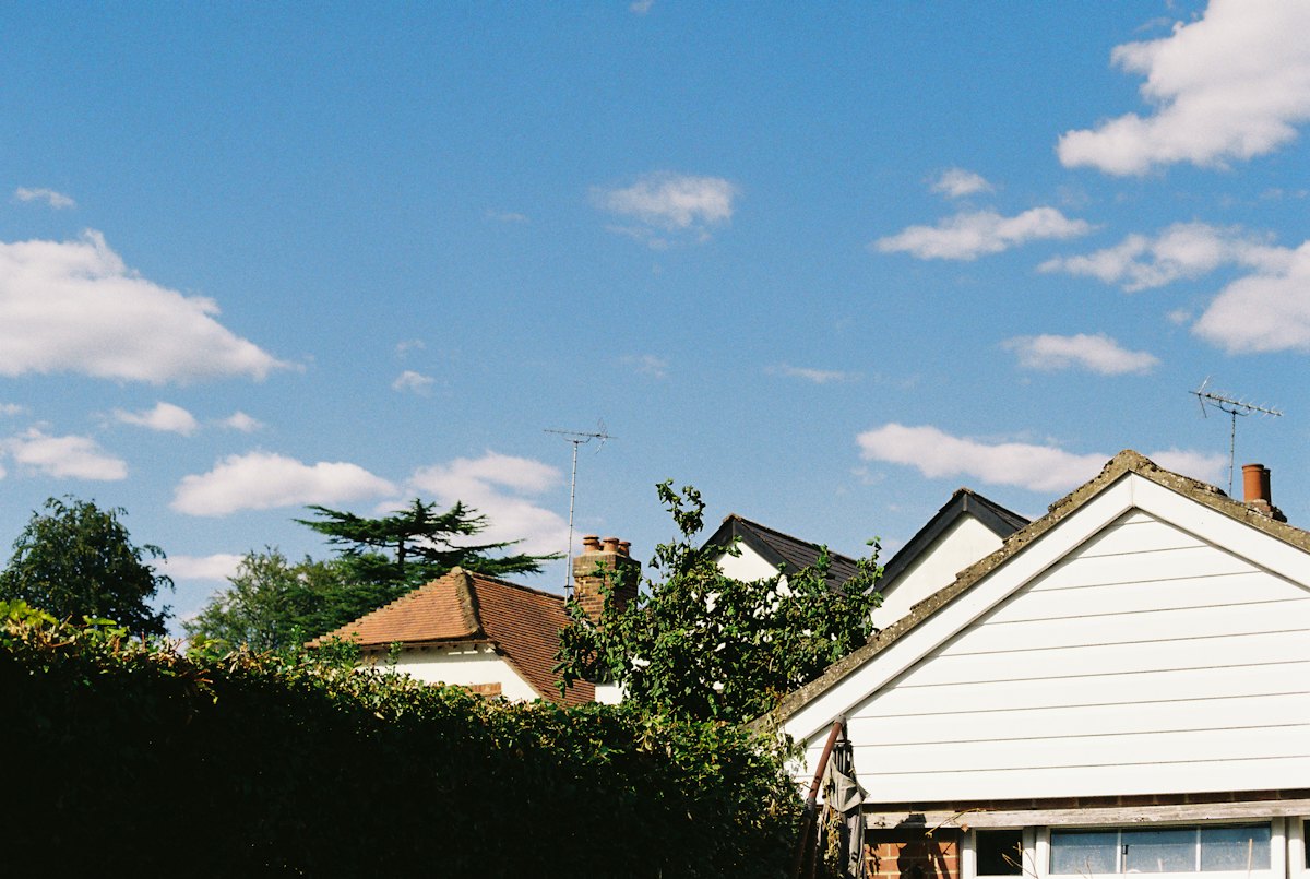 Rooftops and a white weatherboard gable under a blue sky with clouds.